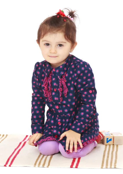Bonita niña sentada en la alfombra . —  Fotos de Stock