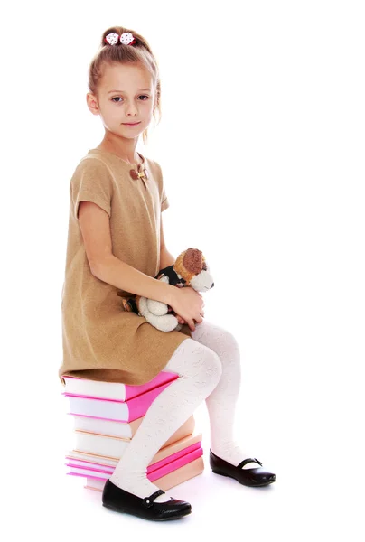 Romantic little girl sitting on a pile of books. — Stock Photo, Image