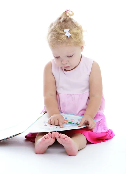 Linda niña sentada en el suelo y leyendo un libro . — Foto de Stock