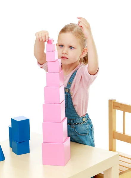 Little girl collects the pink pyramid. — Stock Photo, Image