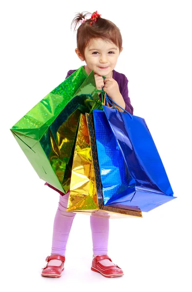 Laughing little girl holds up a lot of multicolored packages. — Stock Photo, Image
