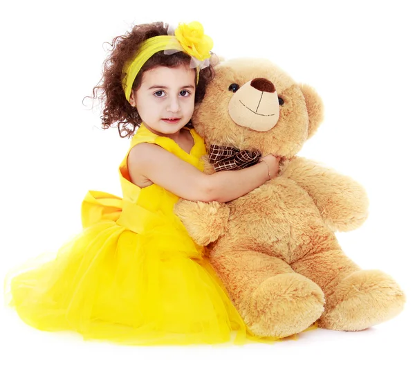 Fashionable dark-haired little girl hugging a bear — Stock Photo, Image