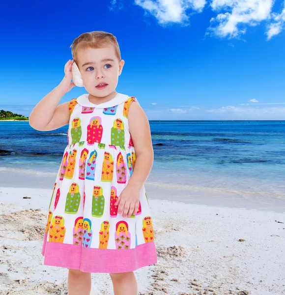 Thoughtful little girl posted a shell to your ear while standing — Stock Photo, Image