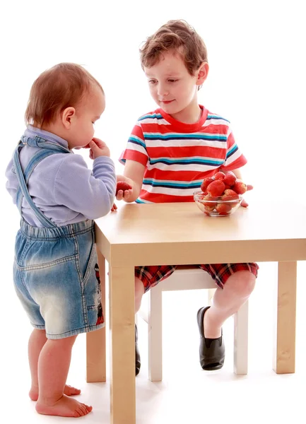 Dois meninos comendo morangos na mesa . — Fotografia de Stock