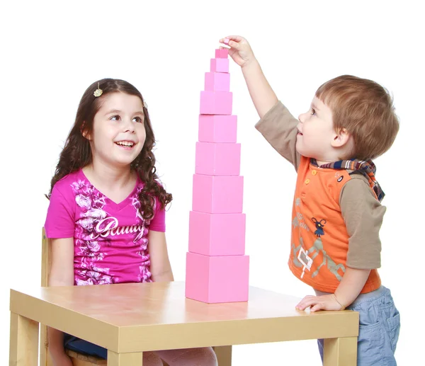 Hermano y hermana construyendo una pirámide roja, escuela Montessori . — Foto de Stock