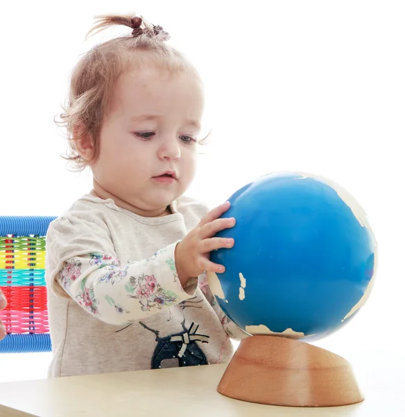 Portrait of a very young girl who turns his hand globe. — Stock Photo, Image