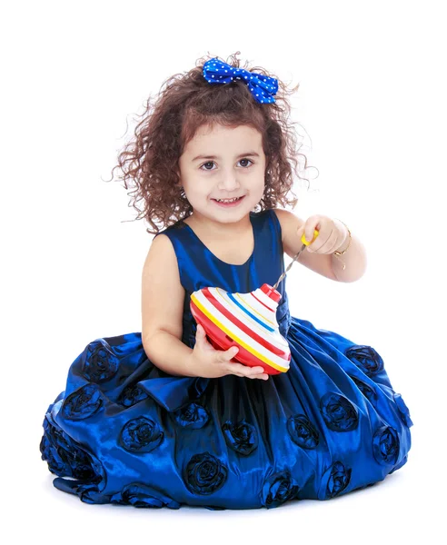 Linda menina sentada no chão e segurando um dreidel — Fotografia de Stock