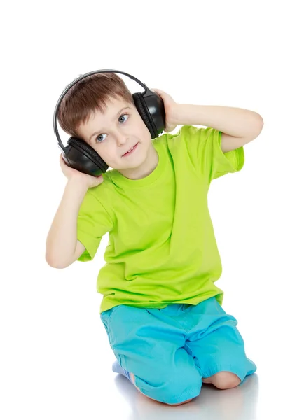 Niño escuchando música a través de auriculares grandes — Foto de Stock