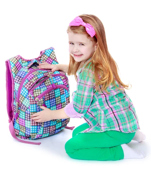 Charming schoolgirl on her knees opens his satchel — Stock Photo, Image