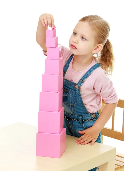 Little girl collects the pink pyramid. — Stock Photo, Image