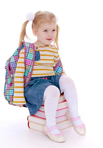 Charming little schoolgirl with satchel behind him sitting on a — Stock Photo, Image