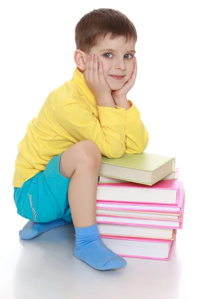 Adorable petit garçon assis à côté d'une pile de livres — Photo