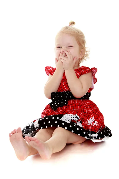 Pretty little girl sitting on the floor and laughing covering mo — Stock Photo, Image