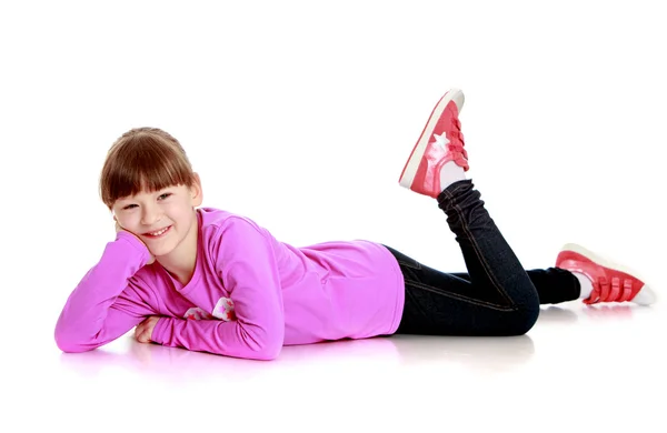 Veselá malá sportovní dívka leží na podlaze — Stock fotografie
