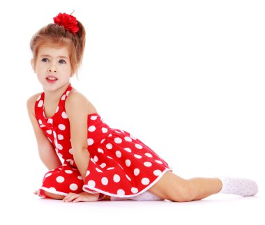 İnci üzerinde oturan beyaz polka noktalı Kırmızı elbiseli küçük bir kız
