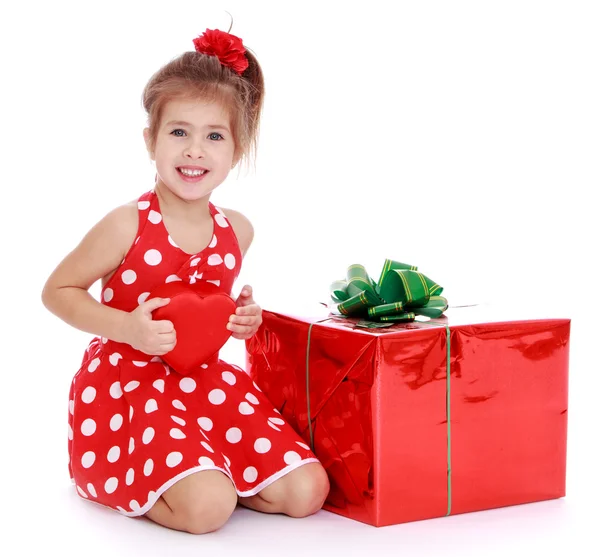 Charming girl in a red dress with white polka dots is holding a — Stock Photo, Image