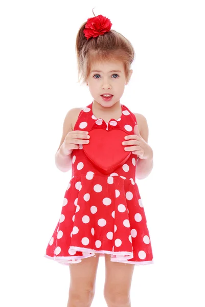 Charming girl in a red dress with white polka dots is holding a — Stock Photo, Image