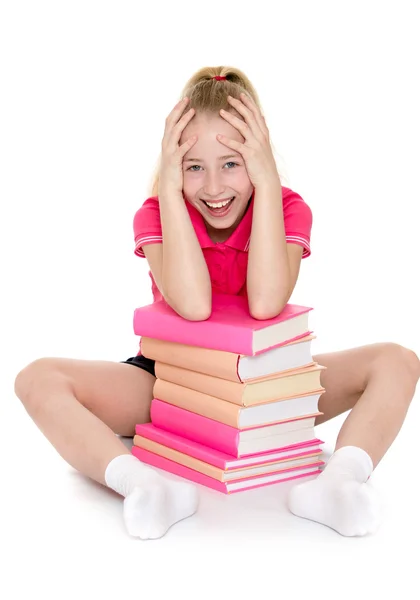 Fille assise avec une pile de livres et tenant sa tête — Photo