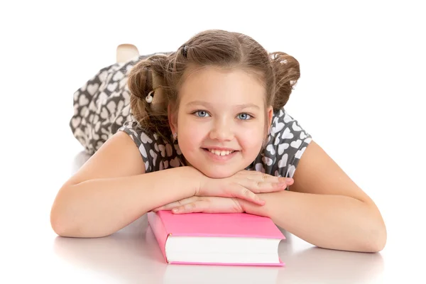 Flicka liggande på golvet med händerna och huvudet på boken. — Stockfoto