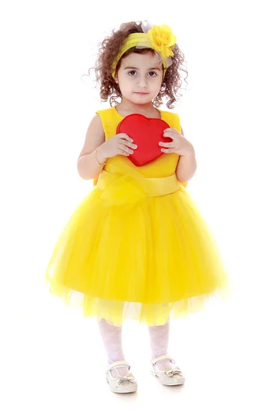 Chica en vestido amarillo sosteniendo el corazón rojo — Foto de Stock