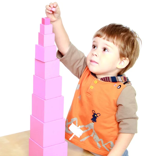 Little boy builds a pink tower. — Stock Photo, Image