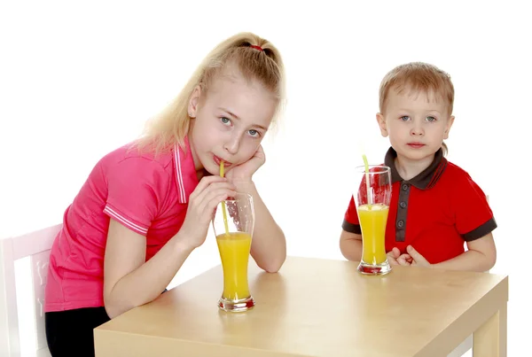 Bror syster dricka juice sitter vid bordet. — Stockfoto
