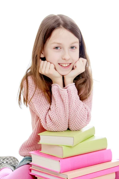 Slim meisje haar ellebogen zetten een stapel boeken. — Stockfoto