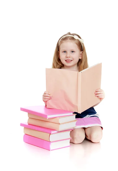 Happy little girl reading a book on her knees — Stock Photo, Image