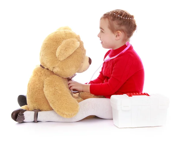 Смішна маленька дівчинка, яка грає лікаря з ведмедем Тедді — стокове фото