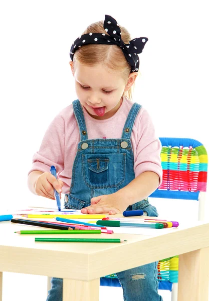 Funny little girl draws with pens sticking out his tongue — Stock Photo, Image