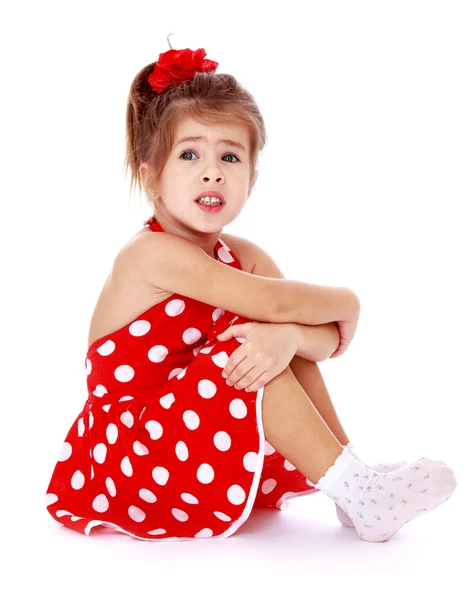 Girl in a red polka-dot dress sitting on the floor — Stock Photo, Image