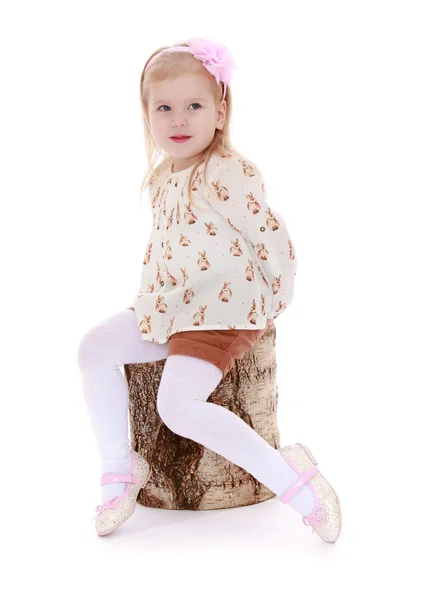 Blond meisje, zittend op een stomp — Stockfoto