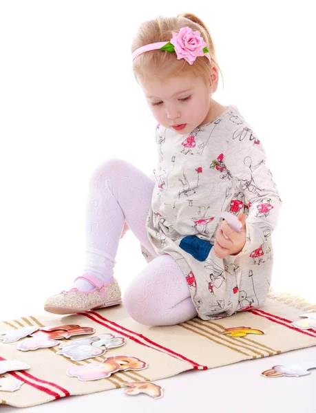 Hermosa niña rubia sentada en la alfombra y juega — Foto de Stock