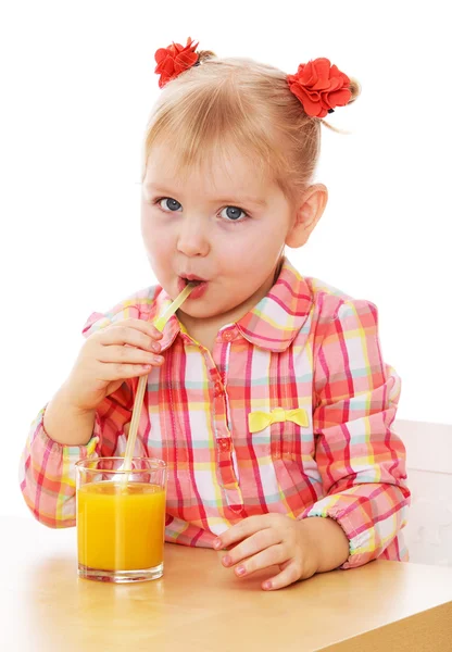 Engraçado menina está bebendo suco de laranja através de uma palha enquanto — Fotografia de Stock