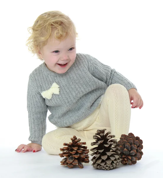 Very little girl sitting on the floor and plays with big pine co — Stock Photo, Image