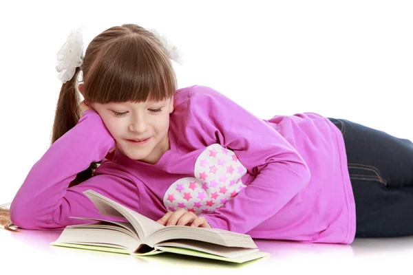 扎着马尾辫的女孩躺在地板上，读一本书 — 图库照片