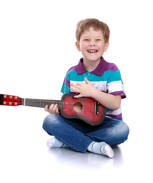 Fröhlicher Junge im gestreiften T-Shirt spielt Gitarre sitzend auf der Flöte — Stockfoto