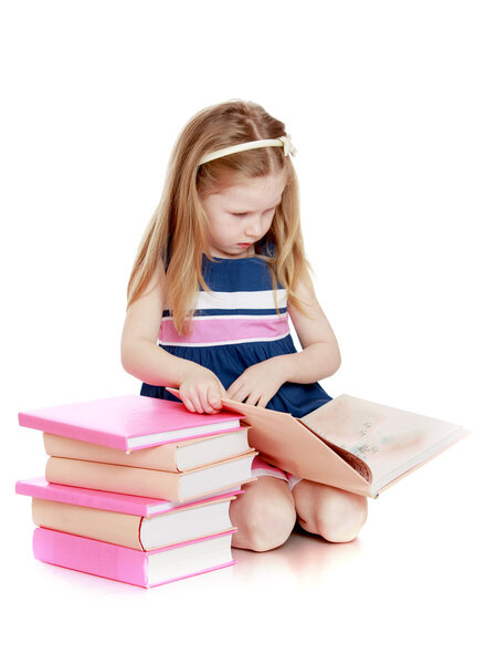 Cute long-haired Caucasian little girl reading a book sitting on