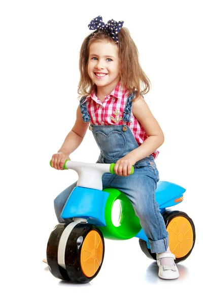 Menina engraçada montando em uma bicicleta de plástico das crianças — Fotografia de Stock