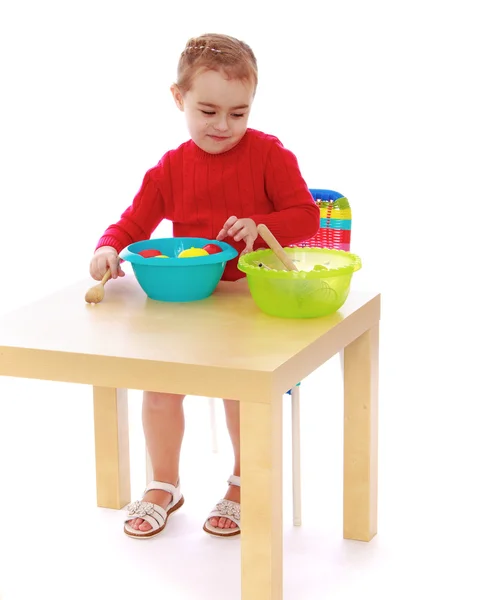 Девушка в детском саду играет в искусственные фрукты сидя на вкладке — стоковое фото
