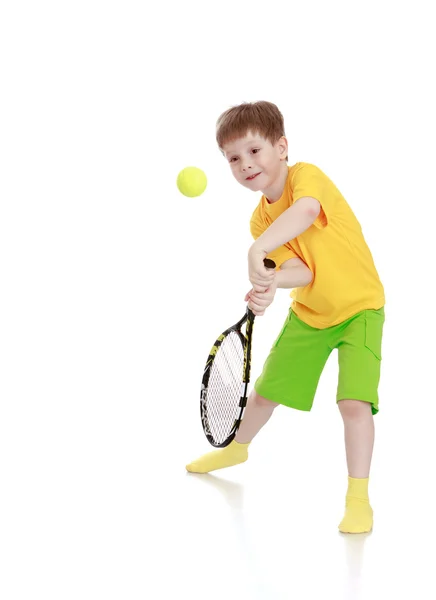 Kleiner Junge mit Tennisschläger, während er den Ball schlägt — Stockfoto