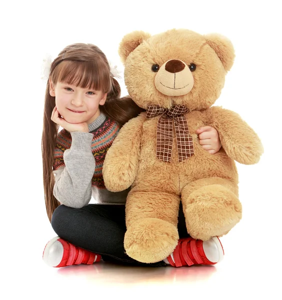 Katta oturan ve bir oyuncak ayı sarılma güzel kız — Stok fotoğraf