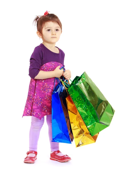 La petite fille tient de grands sacs en papier colorés — Photo