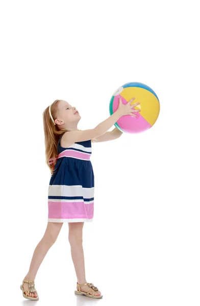 Küçük kız bir plaj topu uzanmış elinde tutan — Stok fotoğraf