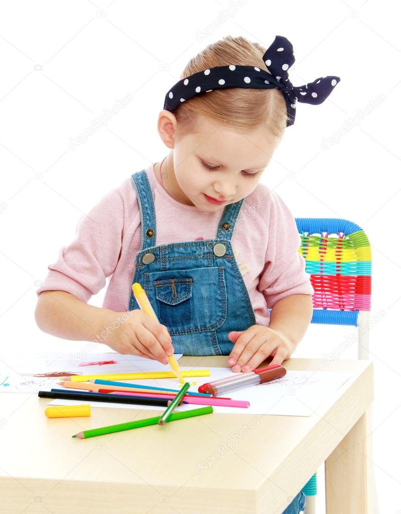 Little girl in denim overalls and a bandage on his head draws wi