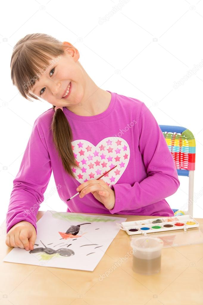 Girl school girl draws paints and brush on a piece of paper sitt