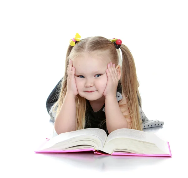 Regordeta niña rubia leyendo un libro tirado en el suelo —  Fotos de Stock