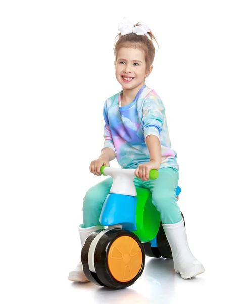Niña en botas de goma está montando en una pequeña bicicleta —  Fotos de Stock