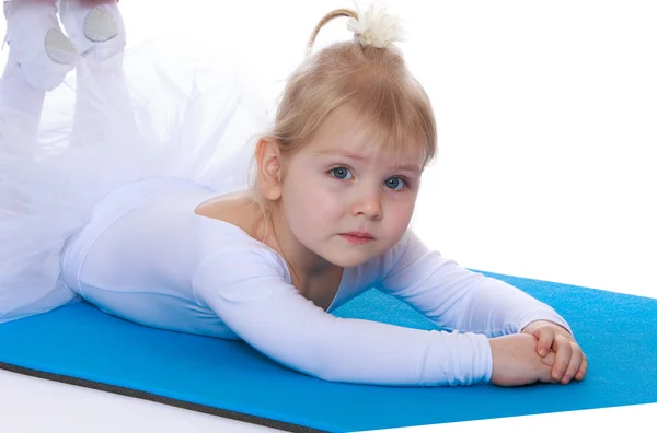 Little girl athlete in a white tracksuit lying on the floor, — Stock Photo, Image