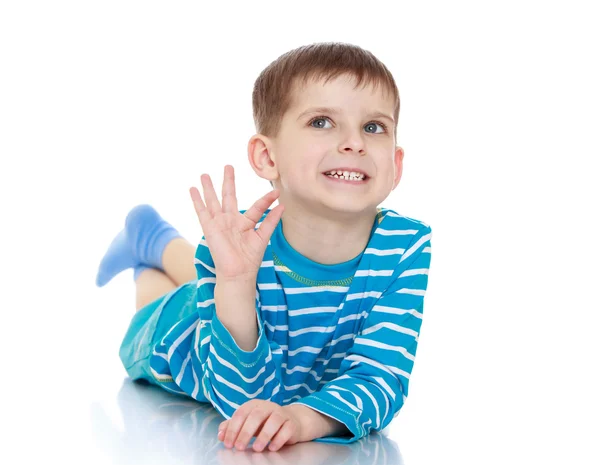 The little boy waved his hand lying on the floor — Stock Photo, Image